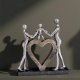 Декоративна статуетка на родители, държащи дете над голямо сърце