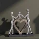 Декоративна статуетка на родители, държащи дете над голямо сърце