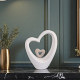 Бяла порцеланова статуетка във формата на голямо сърце с по-малко сърце в центъра