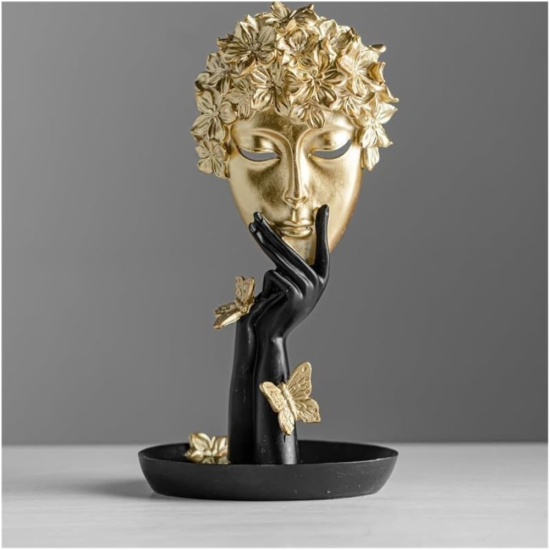 Абстрактна статуетка, изобразяваща черна ръка, която държи златна маска с коса от цветя