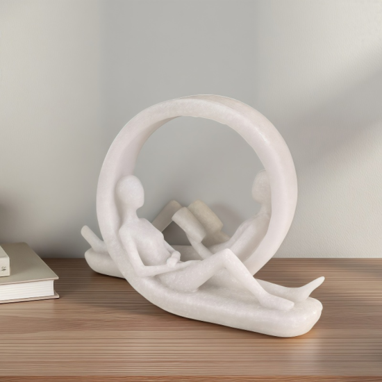 Бяла статуетка с кръгла форма, изобразяваща двама души, четящи книги в легнала поза