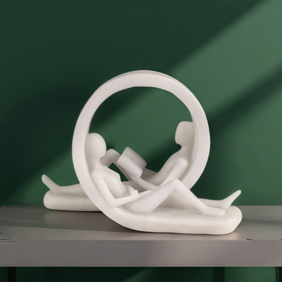 Бяла статуетка с кръгла форма, изобразяваща двама души, четящи книги в легнала поза