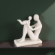 Бяла минималистична статуетка с ефект на камък, изобразяваща майка, която вдига детето си във въздуха