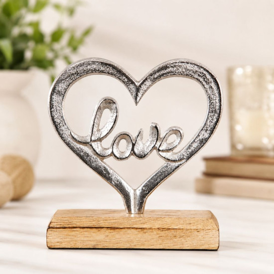 Сребриста метална статуетка сърце с вграден надпис Love върху светлокафява дървена основа